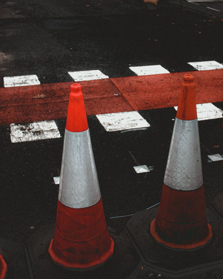 Traffic cones standing beside fresh red and white road markings